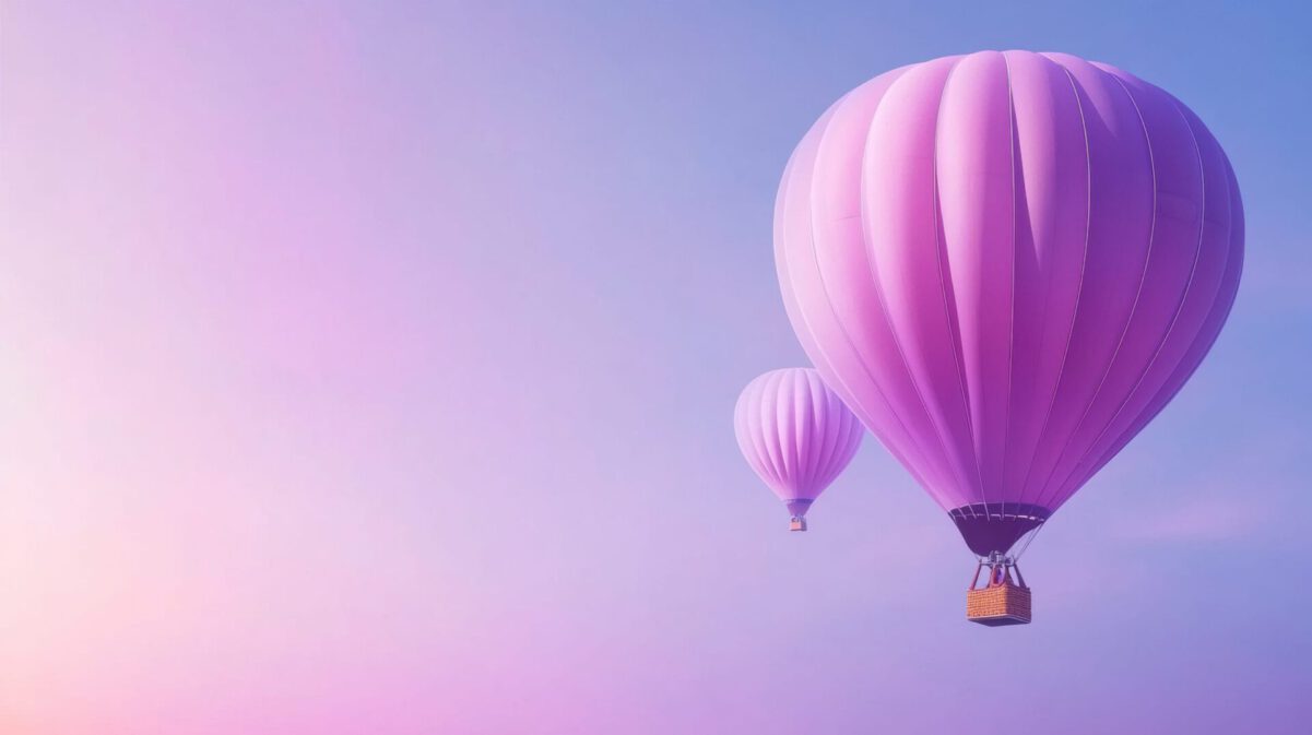 Two pink hot air balloons float against a pastel sky at sunrise.